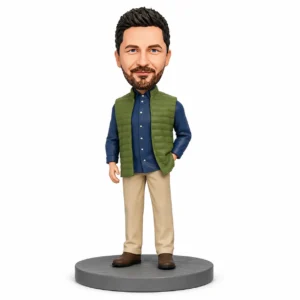 Bobblehead figure of a man with dark hair and beard, wearing a blue shirt, green vest, beige pants, and brown shoes on a gray circular base.