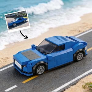 Custom blue car model made from building blocks placed on a road with a beach in the background. A photo of the real car version is shown above the model with an arrow pointing to it