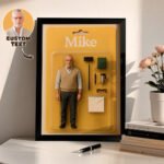 Custom framed action figure display featuring a personalized figurine named Mike with accessories like glasses, notebook, pen, and mug, along with a custom photo and text option