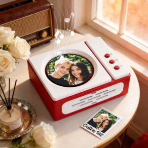 A personalized photo music box with a picture of a couple, musical notes floating above. The box has a retro design with red and white colors, complete with a 'Custom Text' photo card beside it, resting on a table with white roses