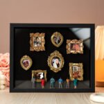 A shadow box with several small golden picture frames containing photos of couples, family moments, and special events. Miniature figurines of people are standing in front of the frames, admiring the photos. The background features soft lighting and decorative elements like roses and pearls