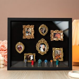 A shadow box with several small golden picture frames containing photos of couples, family moments, and special events. Miniature figurines of people are standing in front of the frames, admiring the photos. The background features soft lighting and decorative elements like roses and pearls