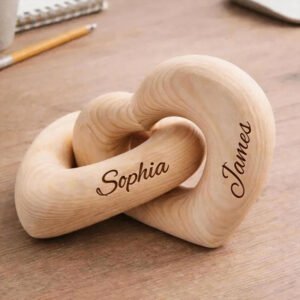 Personalized wooden interlocking heart sculpture engraved with the names Sophia and James, placed on a wooden desk