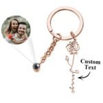 Personalized rose gold keychain with a rose charm, custom name engraving, and a projection photo feature showing a couple’s picture