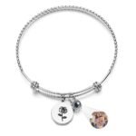 Silver charm bracelet with a rose engraving and a projection bead that displays a hidden couple photo, shown on a plain background