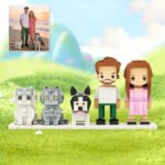 Custom brick figures of a couple with pets based on a real photo, featuring two cats and one dog, displayed on a grassy background with a reference image in the corner