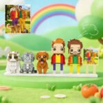 Custom brick figures of two men with their pets, including two cats and one dog, inspired by a photo, displayed on a colorful background with a rainbow and a reference image