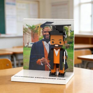 Custom brick figure of a male graduate in cap and gown holding a diploma, displayed on a base labeled “Mechanical Engineering 2026” with a personalized graduation photo backdrop in a classroom setting.