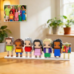Custom brick figures of a multi-generation family displayed on a base, inspired by a reference family photo shown in the corner, placed on a table indoors